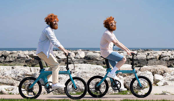 Two men riding electric bikes on the beach