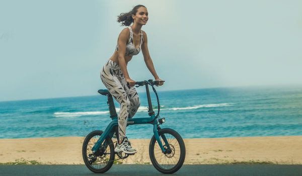 Woman riding electric bicycle by the sea