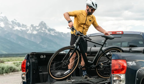 A man is placing a Fiido C21 electric bike into the bed of a truck.