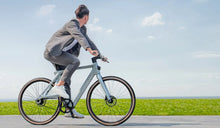 A man rides a Fiido Air electric bike at full speed on the road.