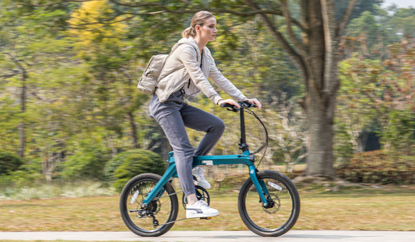 A woman rides a Fiido X electric bike through a lush park