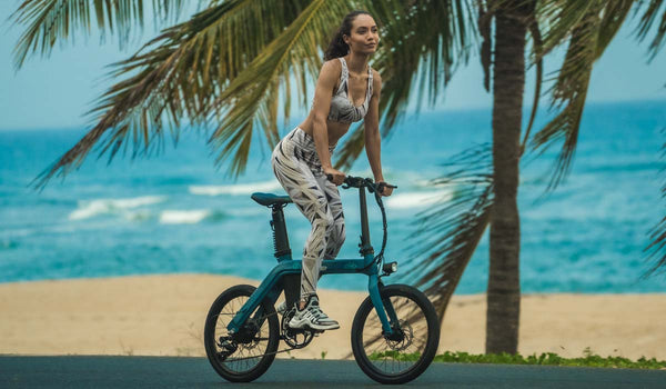 A fit woman is riding a fiido D11 electric bike on the beach