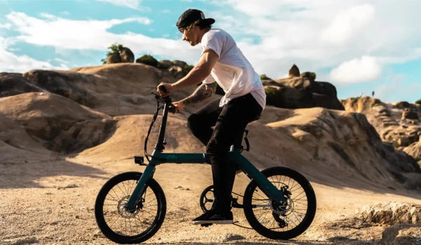 A man is riding a Fiido D11 on rocky terrain.