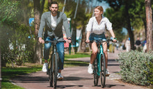 A couple is riding Fiido C21 e-bikes through a park.