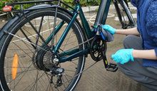 A woman is wiping the frame of a Fiido electric bike.