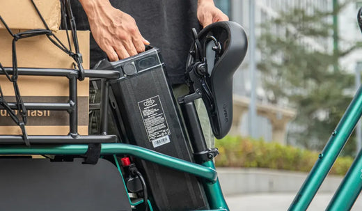A man is removing the external battery of a Fiido T2 electric bicycle.