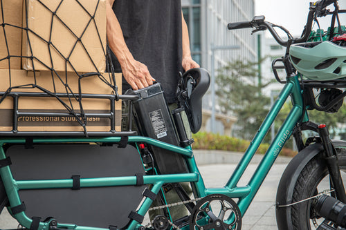 A man is removing the external battery of a Fiido T2 electric bicycle.