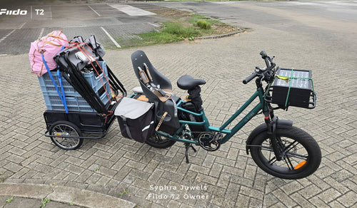 A Fiido T2 cargo e-bike is shown fully loaded with a child seat, side panniers, a front cargo box, and a heavily packed rear trailer.