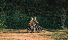 The man is riding a Fiido Titan electric bicycle, preparing for a hunting trip.