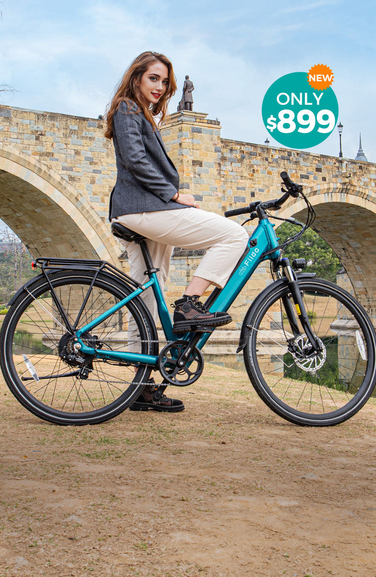 A woman rides a Fiido C11 electric bike by the river under a bridge - m